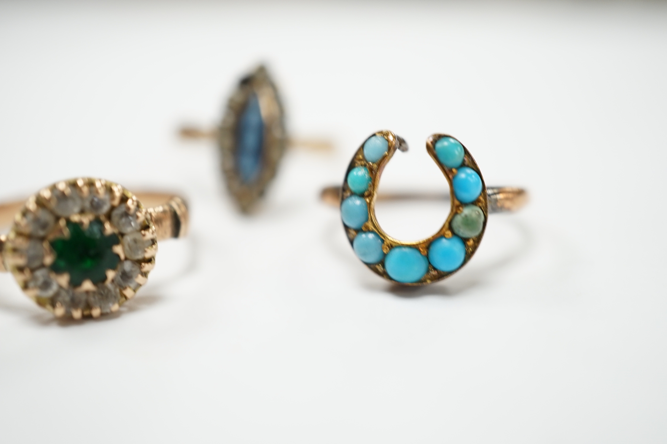 An early 20th century 9ct gold and two colour pastes set circular cluster ring, a 333 (8ct) ring and one other yellow metal and turquoise set horseshoe ring, gross weight 5.6 grams.